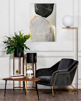 O pictură abstractă cu forme gri, negre și aurii, atârnând într-un interior modern, deasupra unei console din lemn cu o vază și o lumânare, Papilora.