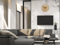 Un ceas de perete modern, cu aspect de lemn și cifre albe, atârnând într-un interior stilat, deasupra unei console din lemn cu o vază și o lumânare, Papilora.