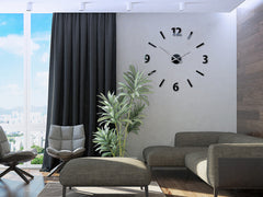 Un ceas de perete minimalist cu cifre negre și linii pe un fundal alb, atârnând într-un interior modern, deasupra unei console din lemn cu o vază și o lumânare, Papilora.