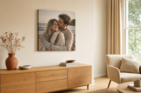 Tabloul cu un cuplu romantic la apus, în culori calde, este agățat într-un interior modern, deasupra unei console din lemn cu o vază și o lumânare, Papilora.