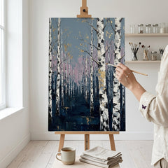 Artistă în atelierul Papilora lângă un șevalet cu tabloul cu pădure de mesteceni, lumină naturală de la fereastră.