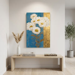 Tablou cu buchet de margarete albe suspendat într-un living modern, deasupra unei console din lemn cu vază și lumânare decorativă.